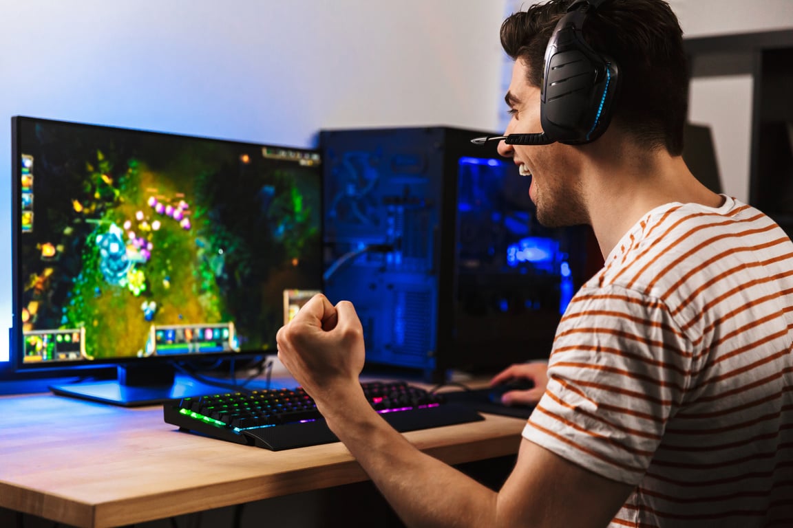 Portrait of Delighted Young Guy Playing Video Games on Computer,